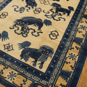 Beige and dark blue patterned rug featuring stylized lions and elaborate geometric borders on wood floorboards.