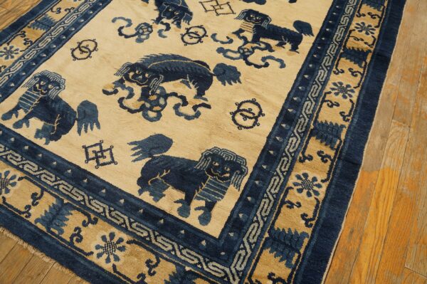 Beige and dark blue patterned rug featuring stylized lions and elaborate geometric borders on wood floorboards.