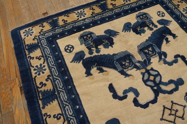 Beige rug featuring a dark blue stylized lion pattern and intricate borders on rustic wood flooring.