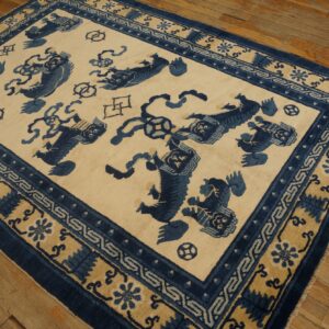 Cream and indigo blue rug featuring stylized animal motifs and geometric borders sits on distressed wood planks.