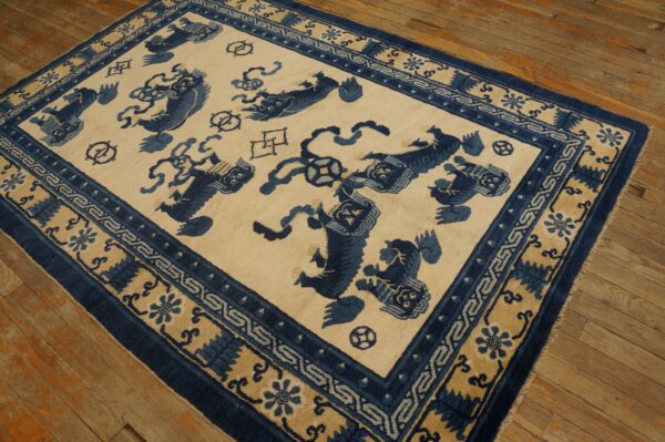 Cream and indigo blue rug featuring stylized animal motifs and geometric borders sits on distressed wood planks.