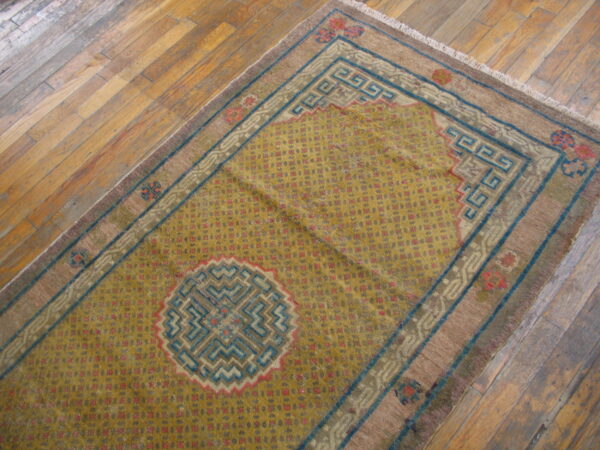 Yellow runner rug featuring geometric red dots, blue greek key borders, and a central medallion on wood.