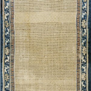 The beige rug features a fine repeating diamond pattern bordered by intricate navy blue floral and fret designs.