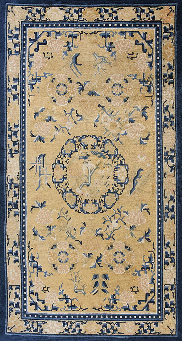 Camel rug with a dark blue border and central medallion surrounded by stylized flowers and birds.