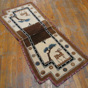 Beige and brown pictorial runner rug depicting deer and trees on distressed wood flooring.