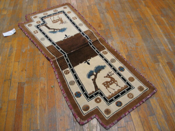 Beige and brown pictorial runner rug depicting deer and trees on distressed wood flooring.