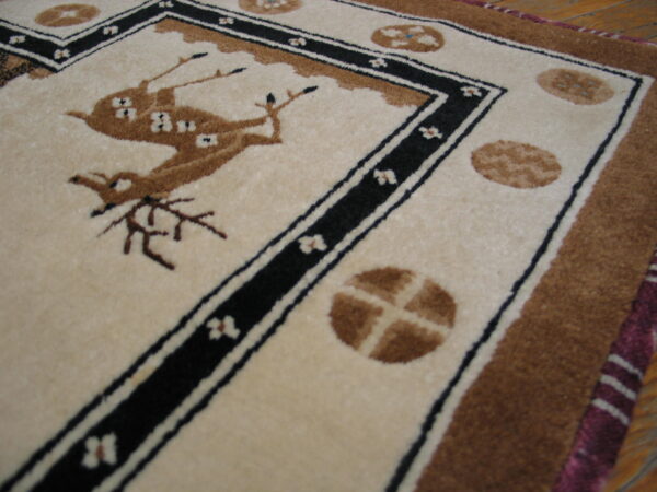 Cream and brown high-pile rug with a central deer design bordered by black and white lines.