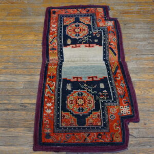 Ornate navy and red rug with a central plain white and light blue panel on plank wood flooring.