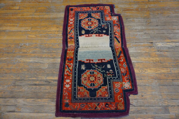Ornate navy and red rug with a central plain white and light blue panel on plank wood flooring.