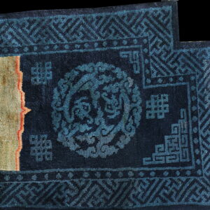 Dark navy rug detail showing bright teal geometric patterns next to a prominent thick beige and orange stripe.