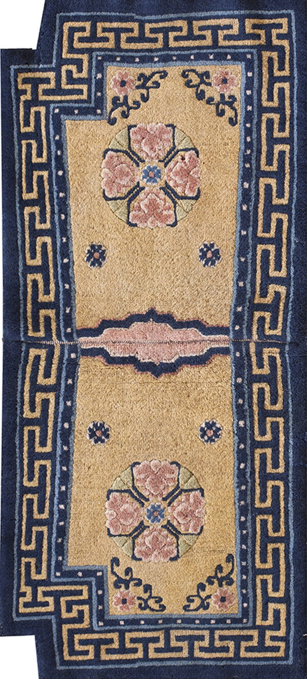 Tan runner rug with dark blue trim, detailed pink florals, and a light blue meander pattern border.