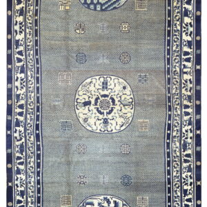 A long slate blue rug detailed with high contrast navy borders and three large central pictorial medallions.