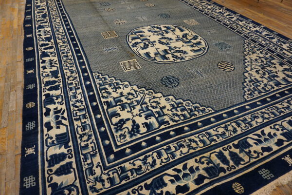 Large indigo and cream rug featuring a complex central medallion and symbolic borders on wooden flooring.