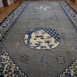 Long blue and cream rug with complex geometric field and circular animal motifs on wood flooring.
