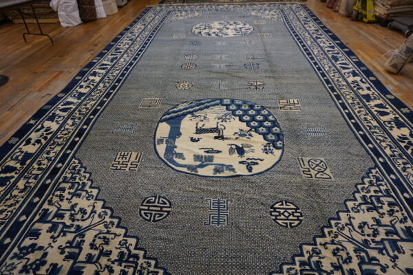 Long blue and cream rug with complex geometric field and circular animal motifs on wood flooring.