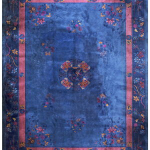 Deep blue rug with scattered colorful floral patterns, a central medallion, and a prominent pink border.