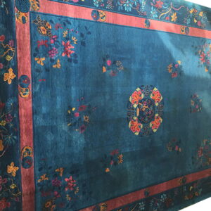 Teal rug featuring a multicolored floral pattern, a central medallion, and a broad rust-colored inner border.