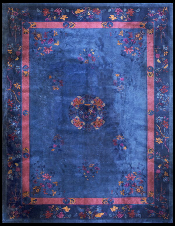 A deep blue rug featuring colorful floral patterns, a central medallion, and an inner mauve border band.