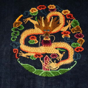 A close-up of a navy rug featuring a large gold dragon medallion surrounded by multicolored clouds.