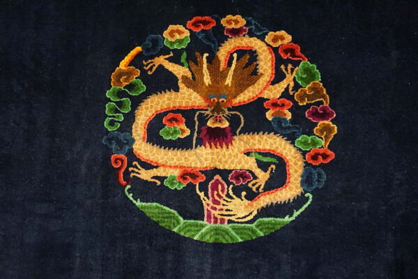A close-up of a navy rug featuring a large gold dragon medallion surrounded by multicolored clouds.