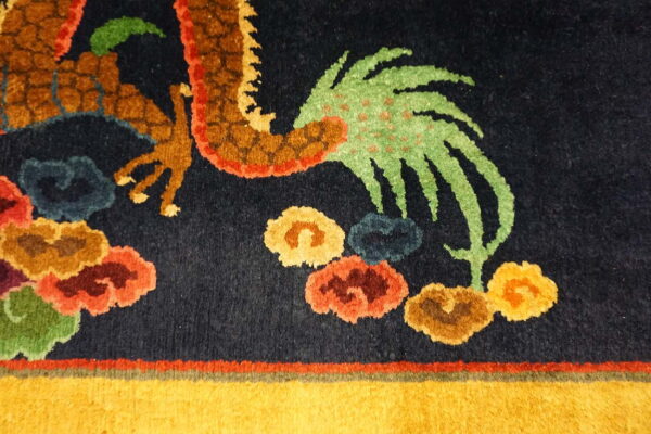 Close-up of a navy rug featuring a multicolored dragon pattern and bright yellow border detail.