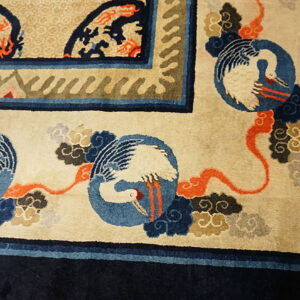 Crane and cloud motifs decorate a cream high-pile rug field with rich blue and orange accents.