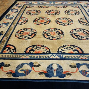 Beige area rug featuring blue and coral dragon medallions and a border of stylized blue cranes on a wood floor.
