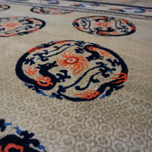 Beige rug with subtle texture, featuring repeating circular navy and orange mythological figures.