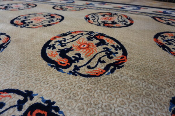 Beige rug with subtle texture, featuring repeating circular navy and orange mythological figures.