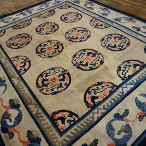 Beige rug with navy and coral medallions and a wide border depicting blue cranes on wood planks.