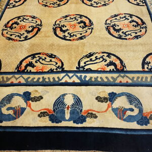 Beige rug with navy and orange stylized dragon medallions and a border featuring blue and white birds.