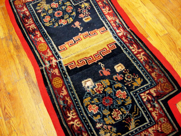 Navy runner rug with red and gold borders features complex traditional patterns on light wood flooring.