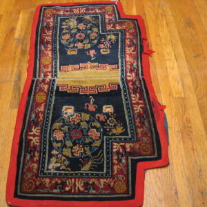 Ornate navy and red mat with gold floral patterns and geometric borders sits on a wood floor.