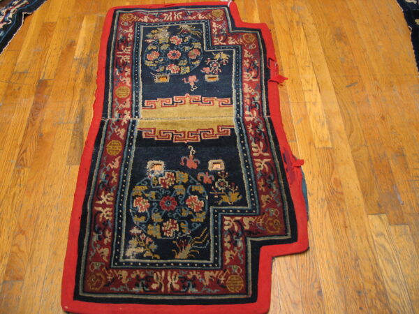 Ornate navy and red mat with gold floral patterns and geometric borders sits on a wood floor.