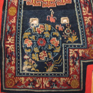 Intricate blue and red patterned rug with gold and light blue details, lying on a honey-toned wood floor.