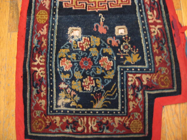 Intricate blue and red patterned rug with gold and light blue details, lying on a honey-toned wood floor.