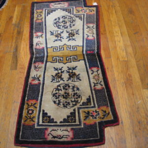 A beige runner rug with stylized dark blue and yellow medallions rests on distressed wood planks.