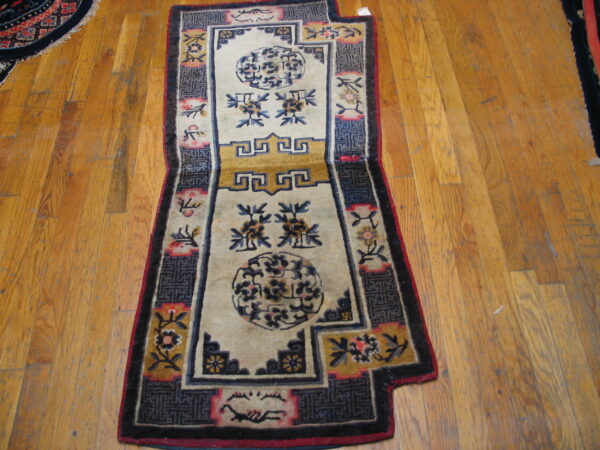 A beige runner rug with stylized dark blue and yellow medallions rests on distressed wood planks.