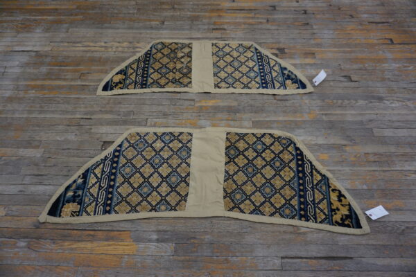 Two matching rugs, featuring blue and gold geometric designs and a cream center seam, rest on wood.
