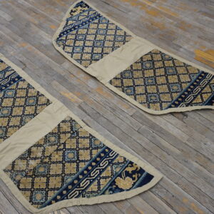 Two low-pile, tapered blue and beige textiles displaying diamond patterns on distressed gray wood.