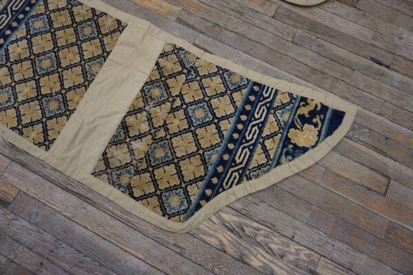Segmented blue and gold low-pile runner with wide beige fabric trim rests on rustic wooden planks.