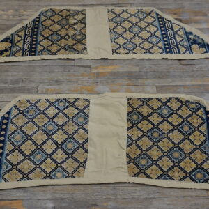 Two coordinating trapezoidal rugs, blue and gold patterned, with plain beige center sections on distressed wood flooring.