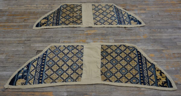 Two coordinating trapezoidal rugs, blue and gold patterned, with plain beige center sections on distressed wood flooring.