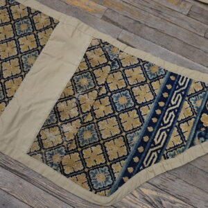 Segmented yellow, pale blue, and dark blue patterned runner with khaki trim lies on rustic wooden planks.