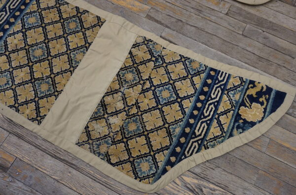 Segmented yellow, pale blue, and dark blue patterned runner with khaki trim lies on rustic wooden planks.