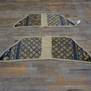 Two fan-shaped rug fragments with blue and gold geometric patterns lie on distressed wood flooring.