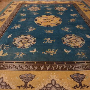 Ornate blue rug with gold borders featuring large medallions and scattered motifs on wood flooring.