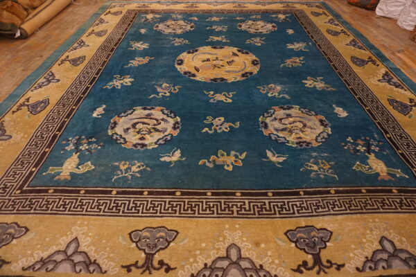 Ornate blue rug with gold borders featuring large medallions and scattered motifs on wood flooring.