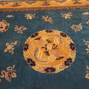 Teal rug featuring a gold central medallion, scattered multicolor motifs, and a contrasting geometric and gold border.