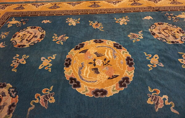 Teal rug featuring a gold central medallion, scattered multicolor motifs, and a contrasting geometric and gold border.